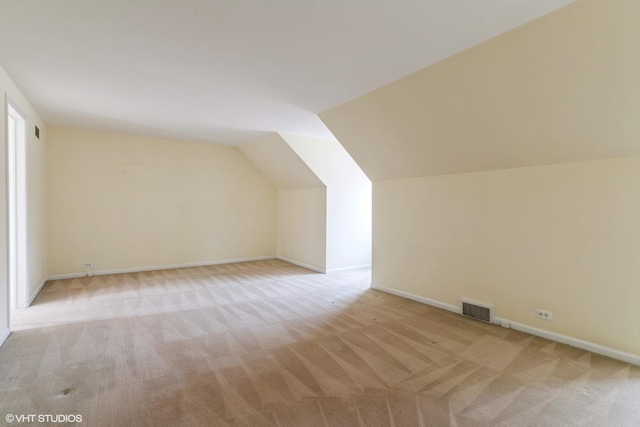 additional living space with light carpet, vaulted ceiling, visible vents, and baseboards