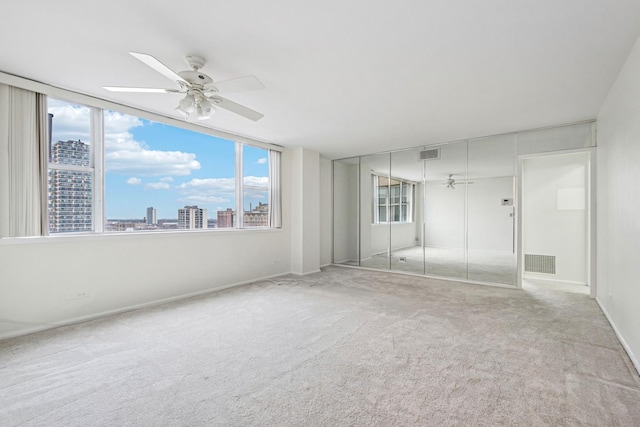 empty room with carpet, visible vents, and a city view