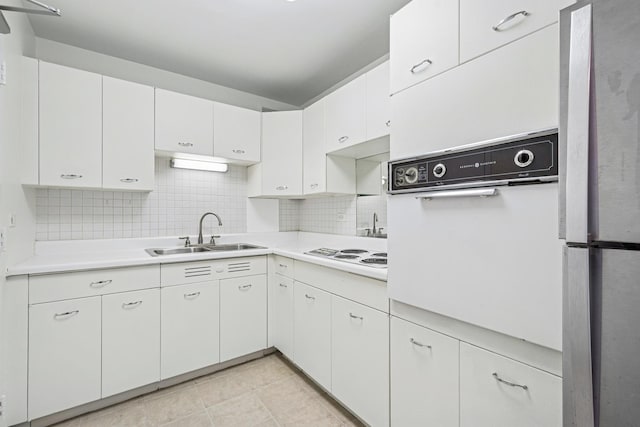 kitchen with white appliances, tasteful backsplash, light countertops, white cabinetry, and a sink