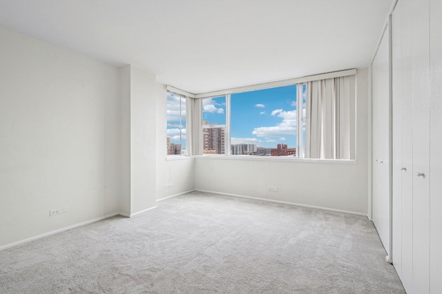 empty room featuring a view of city, carpet, and baseboards