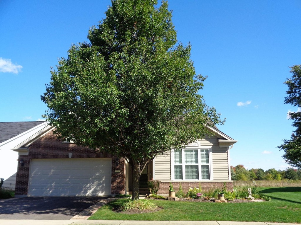 obstructed view of property with driveway, a front yard, a garage, and brick siding