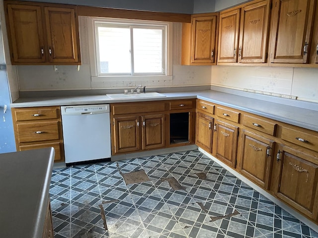 kitchen featuring brown cabinets, white dishwasher, a sink, and tile patterned floors