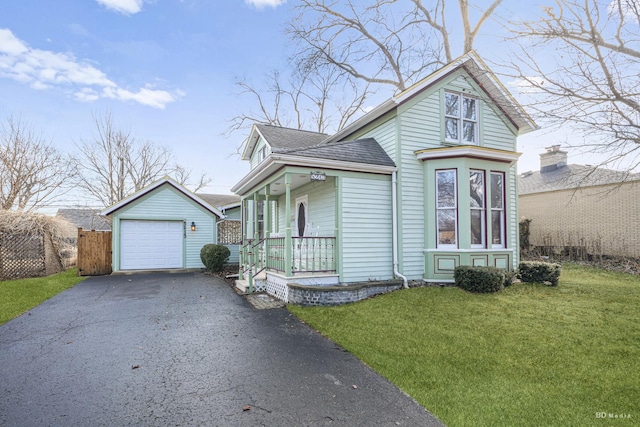 victorian-style house with an outbuilding, aphalt driveway, a porch, fence, and a front lawn