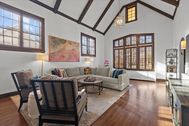 living area with high vaulted ceiling, arched walkways, dark wood finished floors, and a notable chandelier