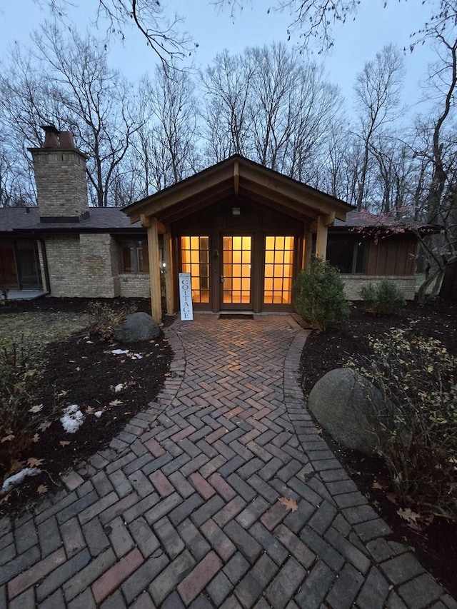 rear view of property featuring stone siding and a chimney