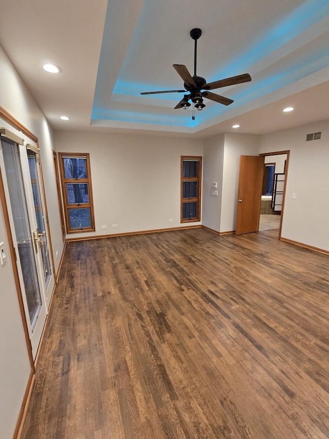 unfurnished living room featuring a raised ceiling, visible vents, and dark wood-style flooring