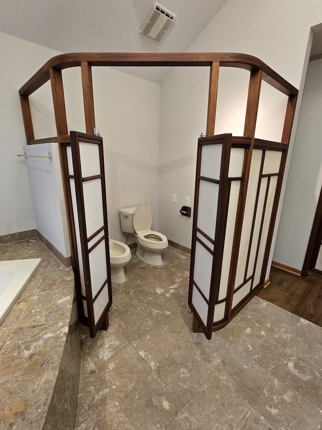 bathroom with a relaxing tiled tub, visible vents, toilet, a bidet, and baseboards