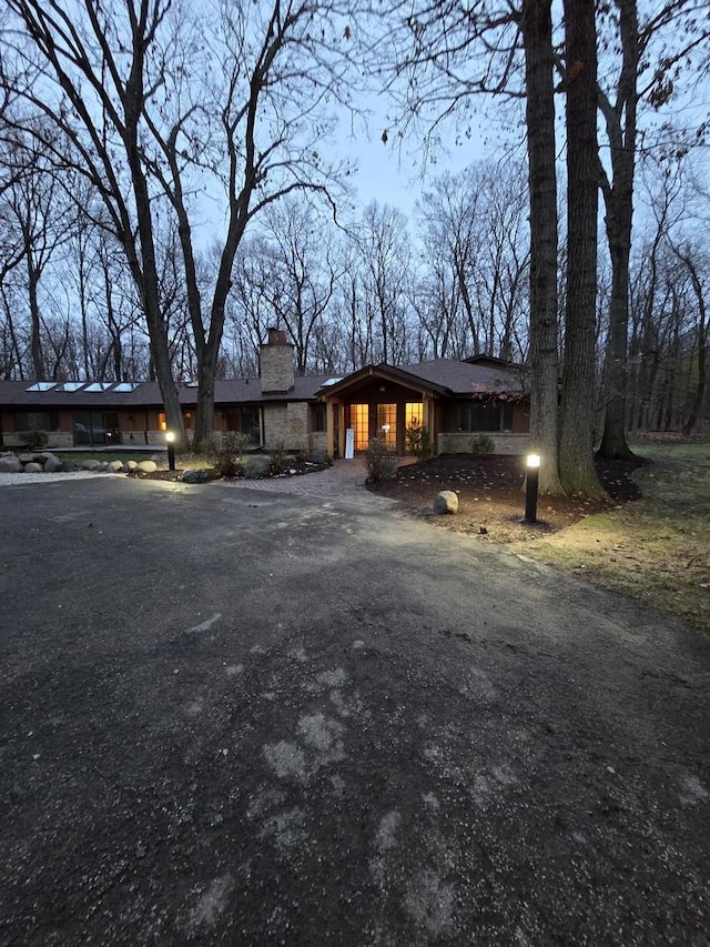 view of front of house featuring stone siding, driveway, and a chimney