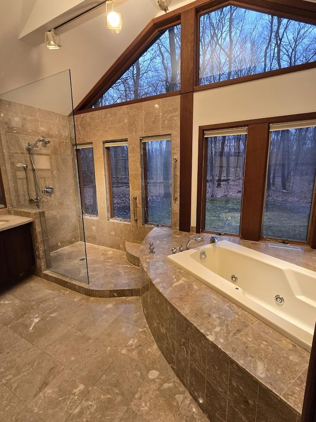 full bathroom featuring high vaulted ceiling, vanity, a wealth of natural light, a tub with jets, and walk in shower