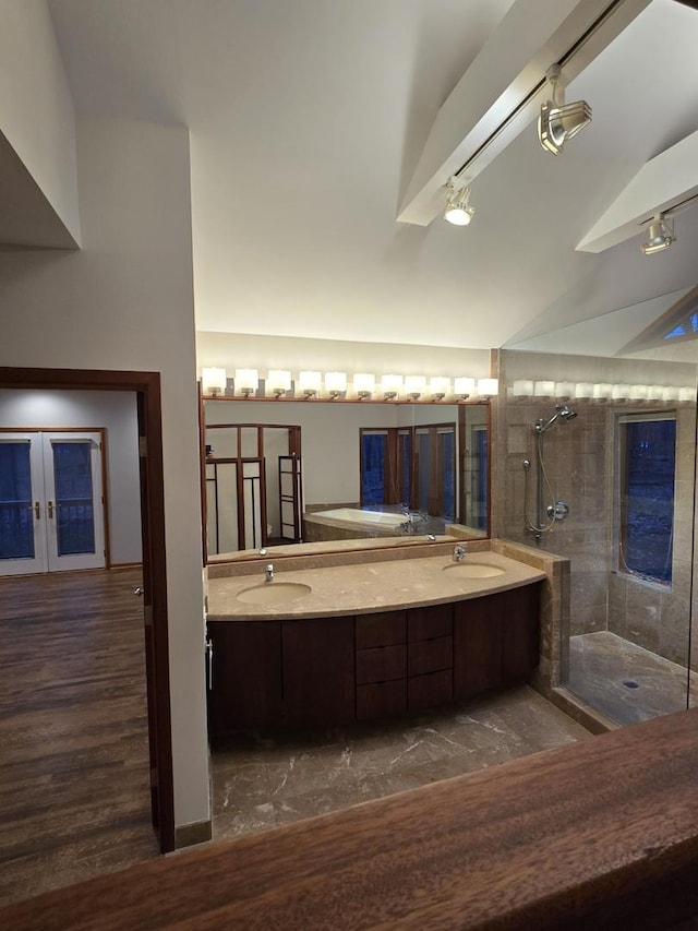 bathroom with double vanity, french doors, tiled shower, and a sink