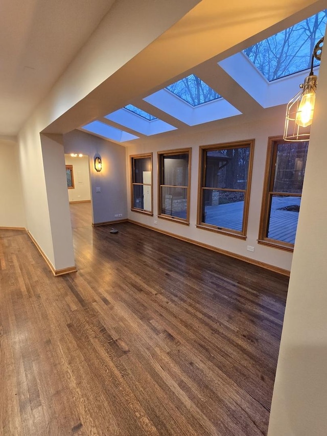 interior space featuring a skylight, baseboards, and wood finished floors