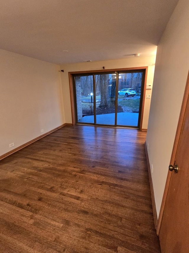 unfurnished room with dark wood-type flooring and baseboards