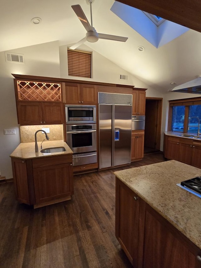 kitchen with vaulted ceiling with skylight, visible vents, a sink, and built in appliances