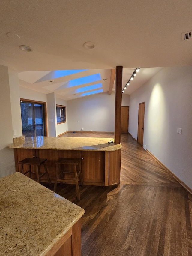 kitchen featuring brown cabinetry, visible vents, dark wood finished floors, and light stone countertops