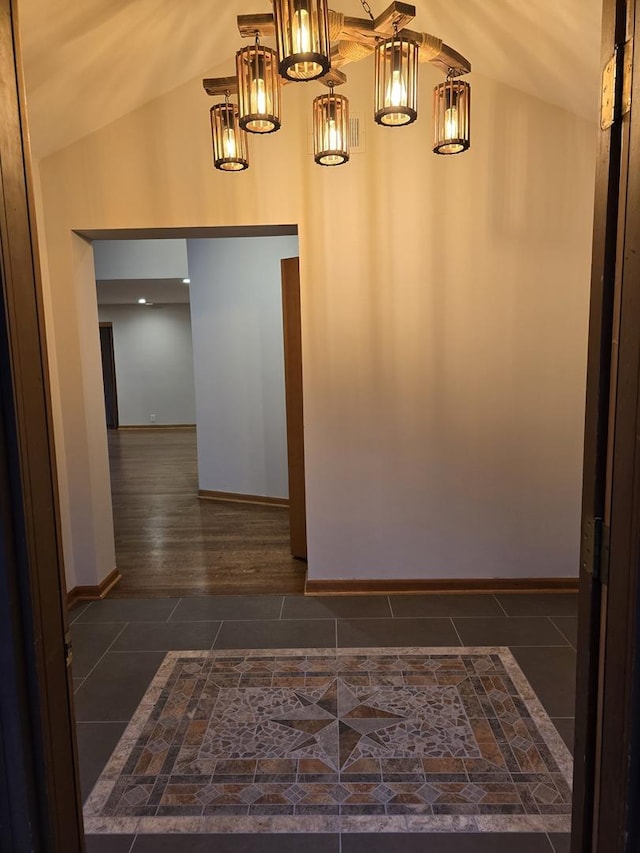 interior space featuring lofted ceiling, dark tile patterned floors, and baseboards