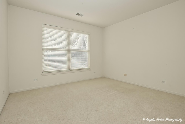 unfurnished room featuring baseboards, visible vents, and light colored carpet