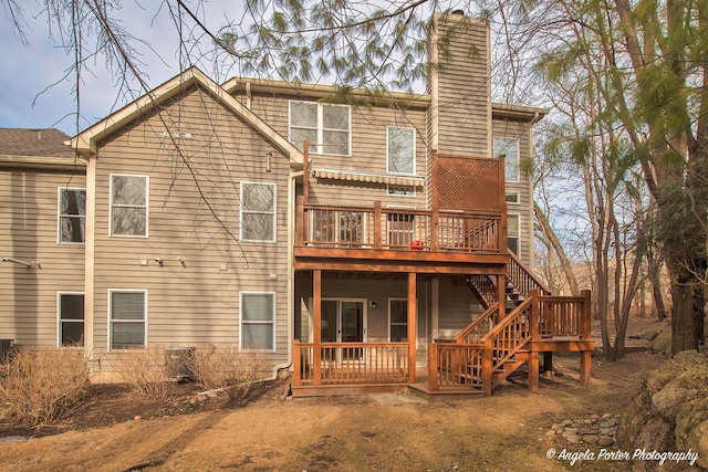 back of property with stairs, a chimney, and a wooden deck