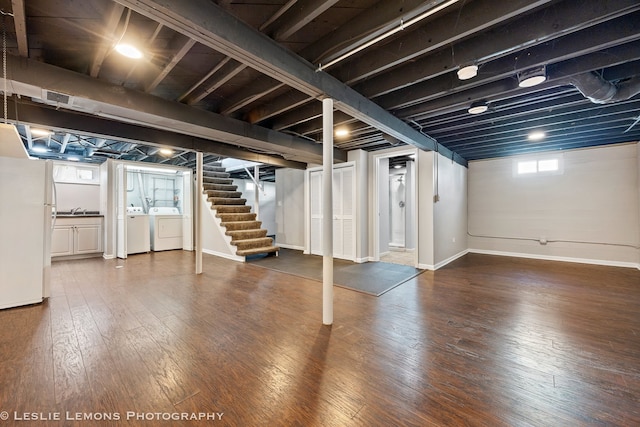 basement with wood-type flooring, stairway, freestanding refrigerator, washing machine and dryer, and a sink