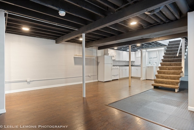 finished basement featuring wood finished floors, baseboards, stairs, freestanding refrigerator, and washing machine and clothes dryer