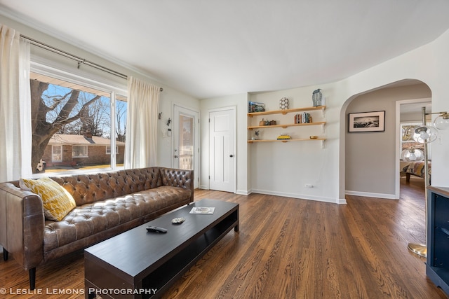 living room with baseboards, arched walkways, and wood finished floors