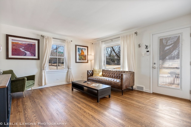 sitting room with baseboards, visible vents, and wood finished floors