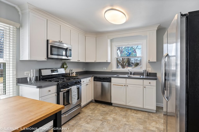 kitchen with stainless steel appliances, white cabinetry, and a sink