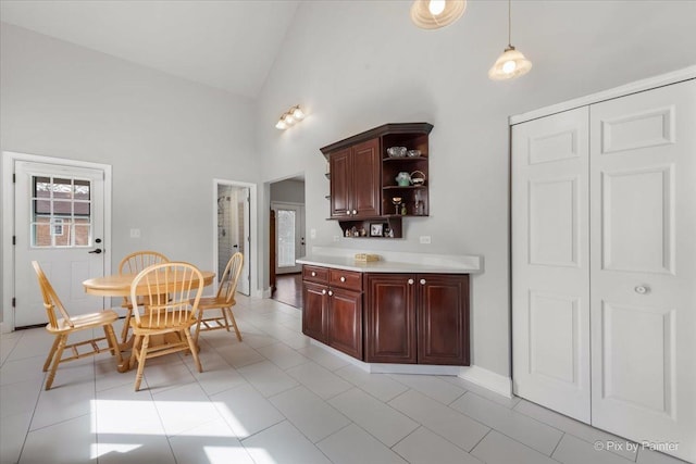 interior space featuring high vaulted ceiling, pendant lighting, open shelves, light tile patterned flooring, and light countertops