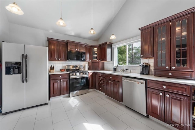 kitchen featuring a sink, hanging light fixtures, light countertops, decorative backsplash, and appliances with stainless steel finishes