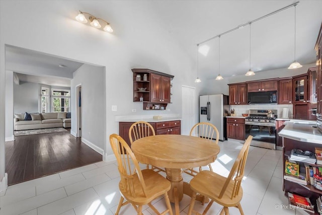 dining area with light tile patterned floors, baseboards, and high vaulted ceiling