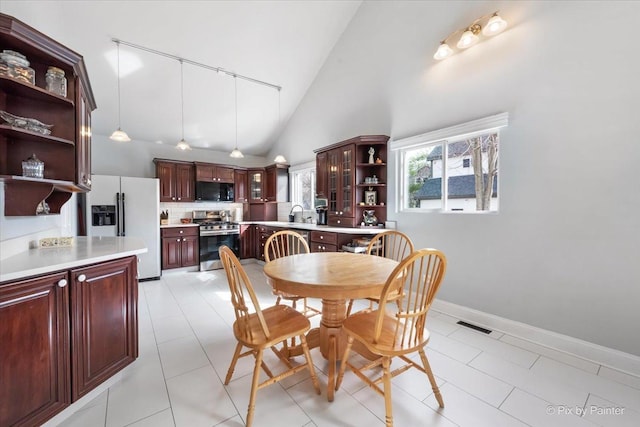 dining space with visible vents, baseboards, high vaulted ceiling, and light tile patterned flooring