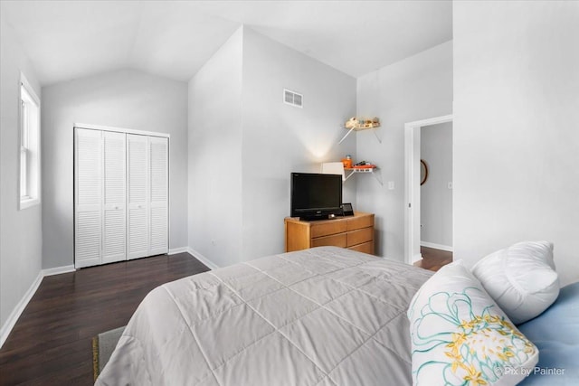 bedroom with baseboards, visible vents, dark wood finished floors, vaulted ceiling, and a closet