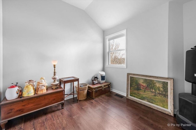 living area with lofted ceiling, wood finished floors, visible vents, and baseboards