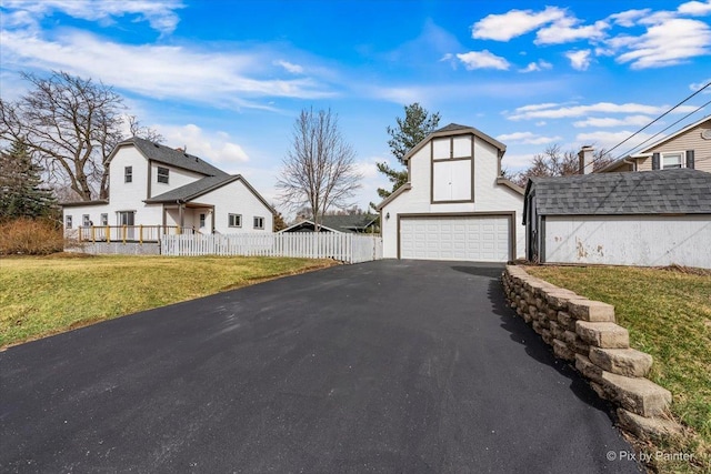 exterior space featuring an outbuilding, fence, a front yard, and aphalt driveway