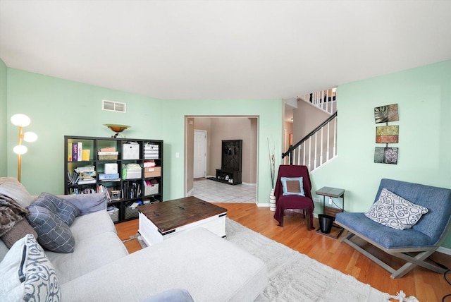 living room featuring wood finished floors, baseboards, stairs, and visible vents