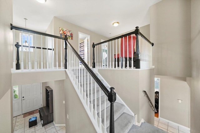 staircase with baseboards, a high ceiling, and tile patterned flooring