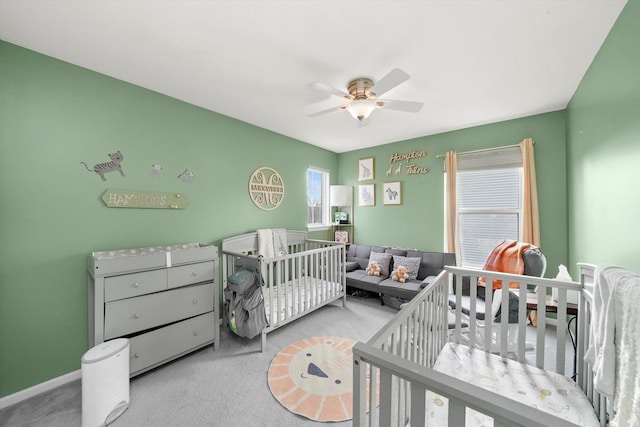bedroom featuring baseboards, a nursery area, ceiling fan, and carpet