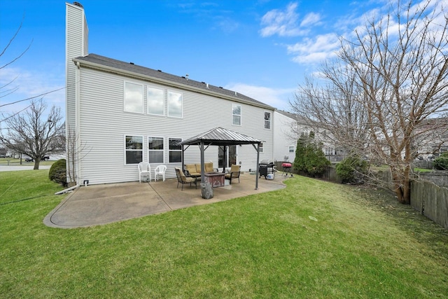 back of house featuring fence, a lawn, a gazebo, a patio area, and a chimney