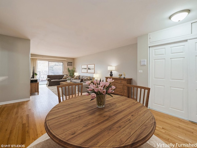 dining area featuring a wall unit AC and light wood-style flooring