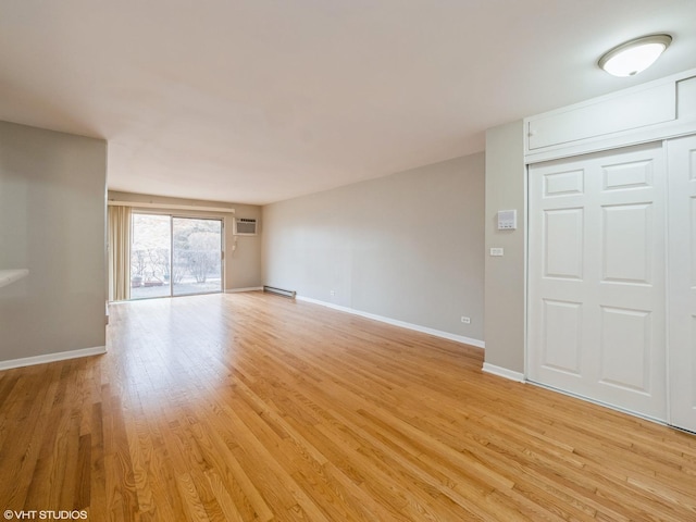 unfurnished living room featuring light wood-type flooring, an AC wall unit, baseboards, and baseboard heating