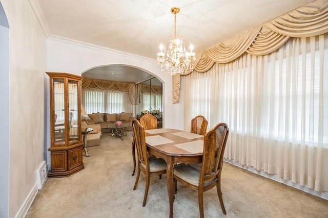 carpeted dining room with visible vents, arched walkways, a notable chandelier, and ornamental molding