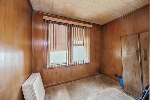 unfurnished room with baseboards, radiator heating unit, and wooden walls