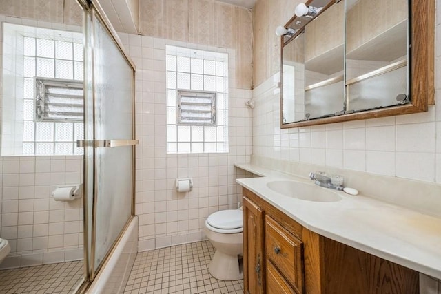 full bath featuring plenty of natural light, tile patterned flooring, toilet, and tile walls