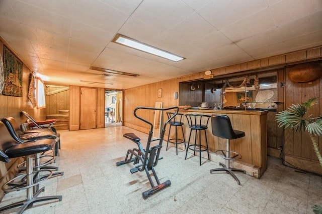 exercise room with a dry bar, wood walls, and tile patterned floors