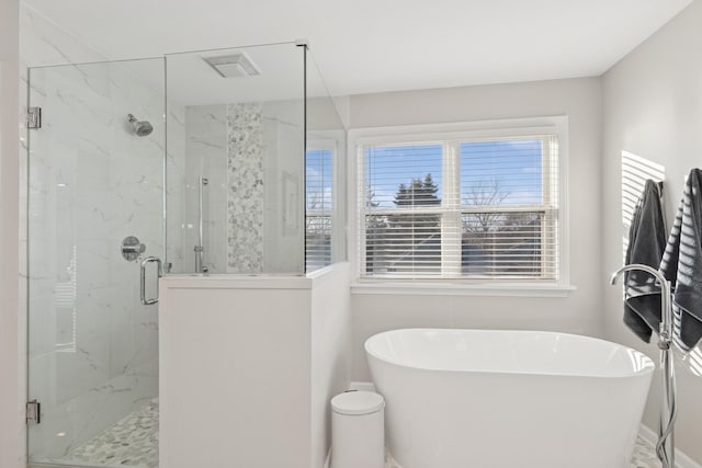 bathroom with a freestanding tub and a marble finish shower