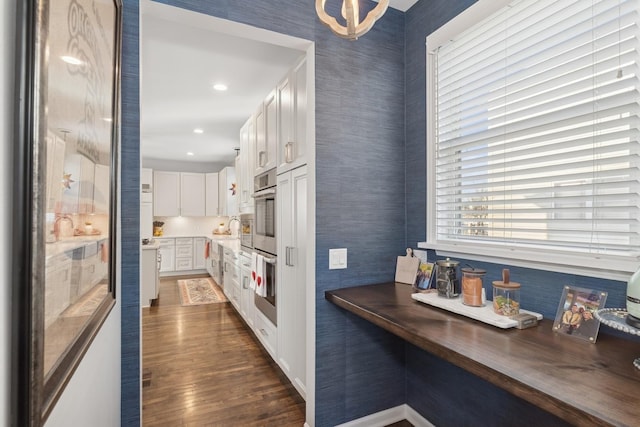 kitchen featuring stainless steel double oven, a sink, white cabinetry, wooden counters, and dark wood-style floors