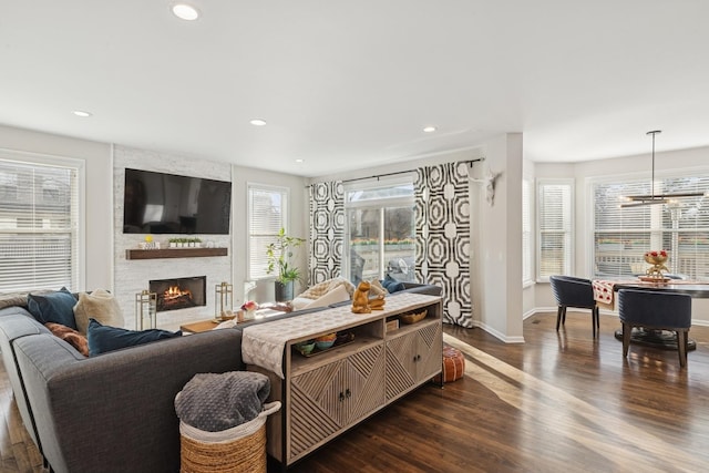 living area featuring baseboards, a stone fireplace, dark wood-style flooring, and recessed lighting