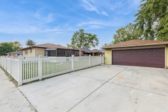 ranch-style house featuring a garage, a fenced front yard, and an outbuilding