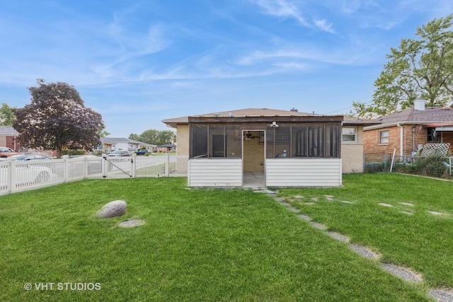 rear view of house featuring a yard, a fenced backyard, a gate, and a sunroom