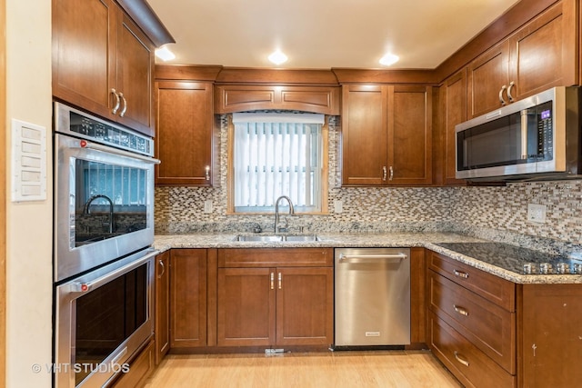 kitchen with stainless steel appliances, a sink, decorative backsplash, and light stone countertops