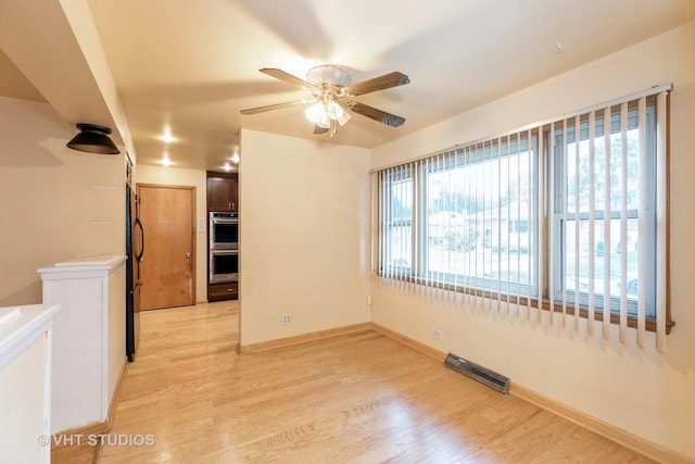 unfurnished room with baseboards, visible vents, ceiling fan, and light wood finished floors